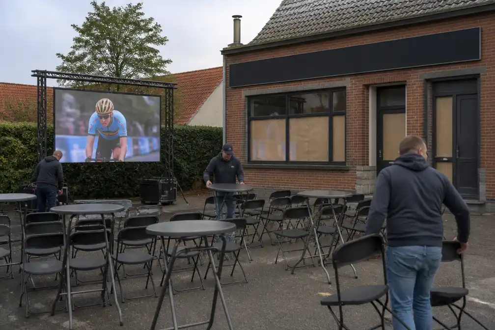 Supporters van Remco Evenepoel volgen WK op groot scherm op parking van gesloten café